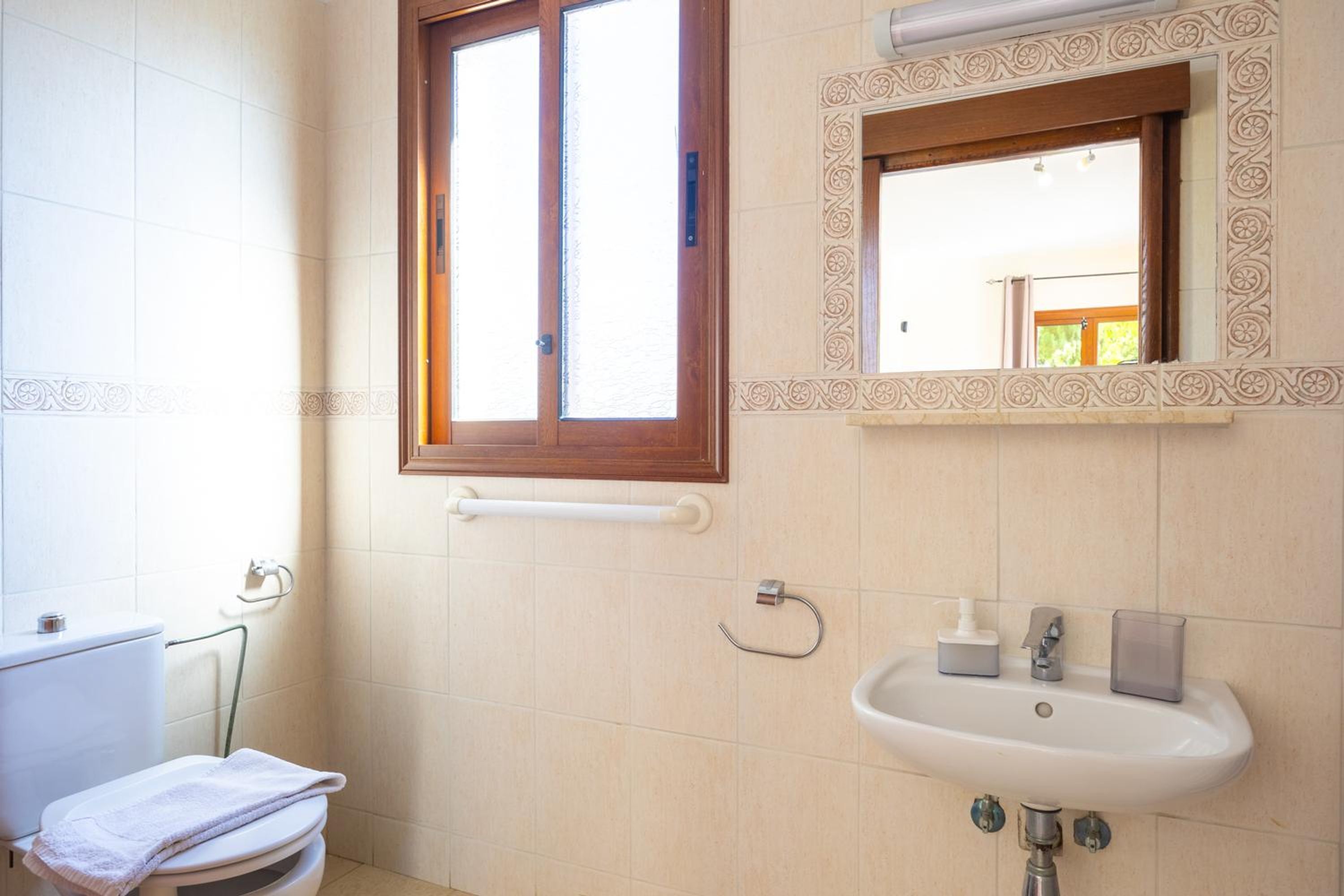 Baño con inodoro, lavabo y ventana.
