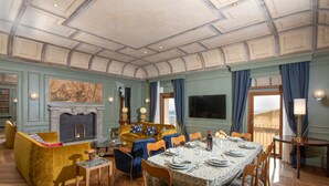 A dining room with a high ceiling, a fireplace, a large painting, and a view of the outside. - Belvedere Guastella A 8 Emma Villas (Noto)