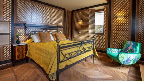 Ein Schlafzimmer mit einem Bett, einem Nachttisch, einem Sessel und einem Fenster mit Blick.