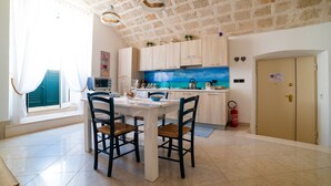 A kitchen with a stone ceiling, wooden cabinets, a blue backsplash, and a dining area with chairs and a table. - Gioia Casa Vacanze in Monopoli (Monopoli)