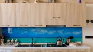 A kitchen with wooden cabinets, a blue backsplash, and a view of the ocean. - Gioia Casa Vacanze in Monopoli (Monopoli)
