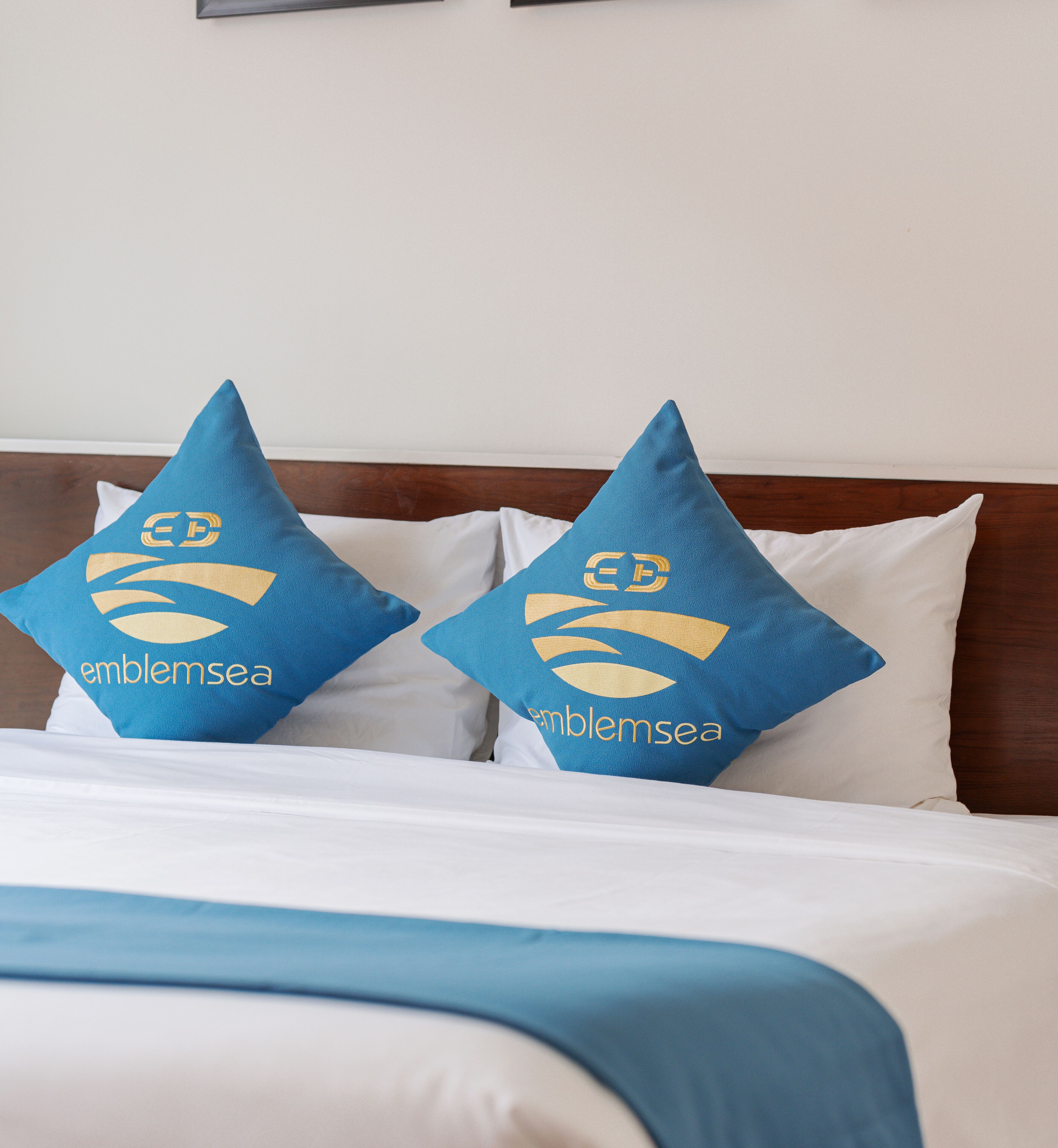 Ein Bett mit zwei Kissen, versehen mit einem Logo und dem Schriftzug "emblemsea".