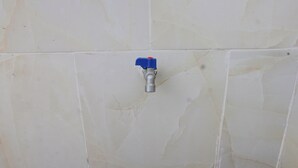 A bathroom with a white tiled wall and a visible plumbing fixture.