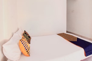 Una cama con ropa blanca, una manta azul y dos almohadas con estampado de lunares.