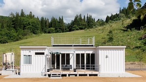 A white building with a balcony, large windows, and a covered outdoor area. - Gram Cottage Hakuba (Hakuba)