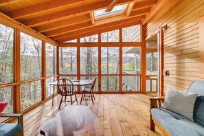A wooden cabin with a large glass windowed porch, a dining table with chairs, and a sofa. - Great Barrington Lakeside Getaway w/ Kayak & Grill (Great Barrington)