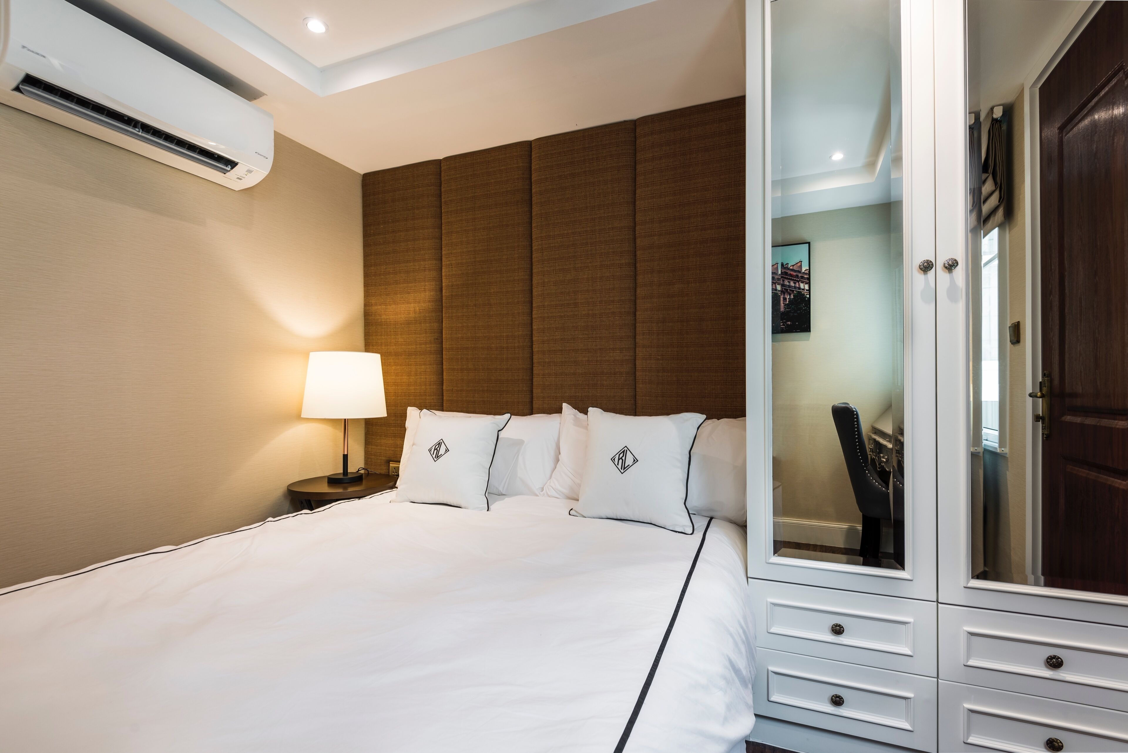 Habitación de hotel con cama, lámpara de noche, armario y unidad de aire acondicionado.
