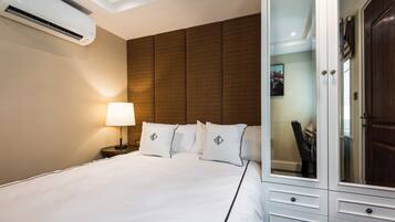 Habitación de hotel con cama, lámpara de noche, armario y unidad de aire acondicionado.