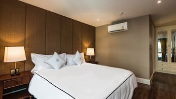 A hotel room with a large bed, two bedside lamps, an air conditioning unit, and a wardrobe.