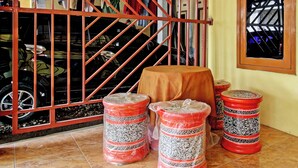 A room with a tiled floor, a table with a brown tablecloth, and decorative red and white patterned stools. - Hotel O Juan Kostel (Kembaran)