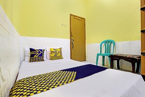 A room with a bed, a wooden door, a blue chair, and a small table. - Hotel O Juan Kostel (Kembaran)