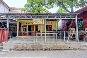A yellow building with a signboard advertising a cost-effective service. - Hotel O Juan Kostel (Kembaran)