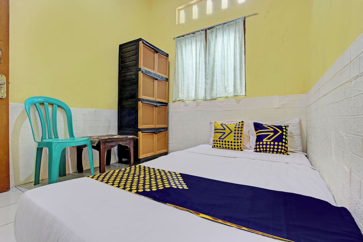Quarto com cama, cadeira, armário e janela com cortinas.