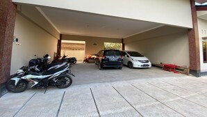 Un área de estacionamiento techada con una motocicleta, un automóvil y una bicicleta.
