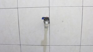 Un baño con paredes de azulejos blancos y un grifo a la vista.