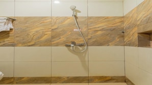 Une douche équipée d’un pommeau de douche à main et d’un robinet de contrôle fixé au mur.
