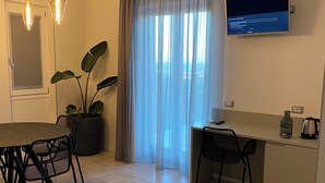 Un soggiorno moderno con zona pranzo, TV a parete e un'ampia finestra con tende.