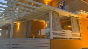 Una casa moderna a due piani con un balcone, una pergola e un ingresso ben illuminato.