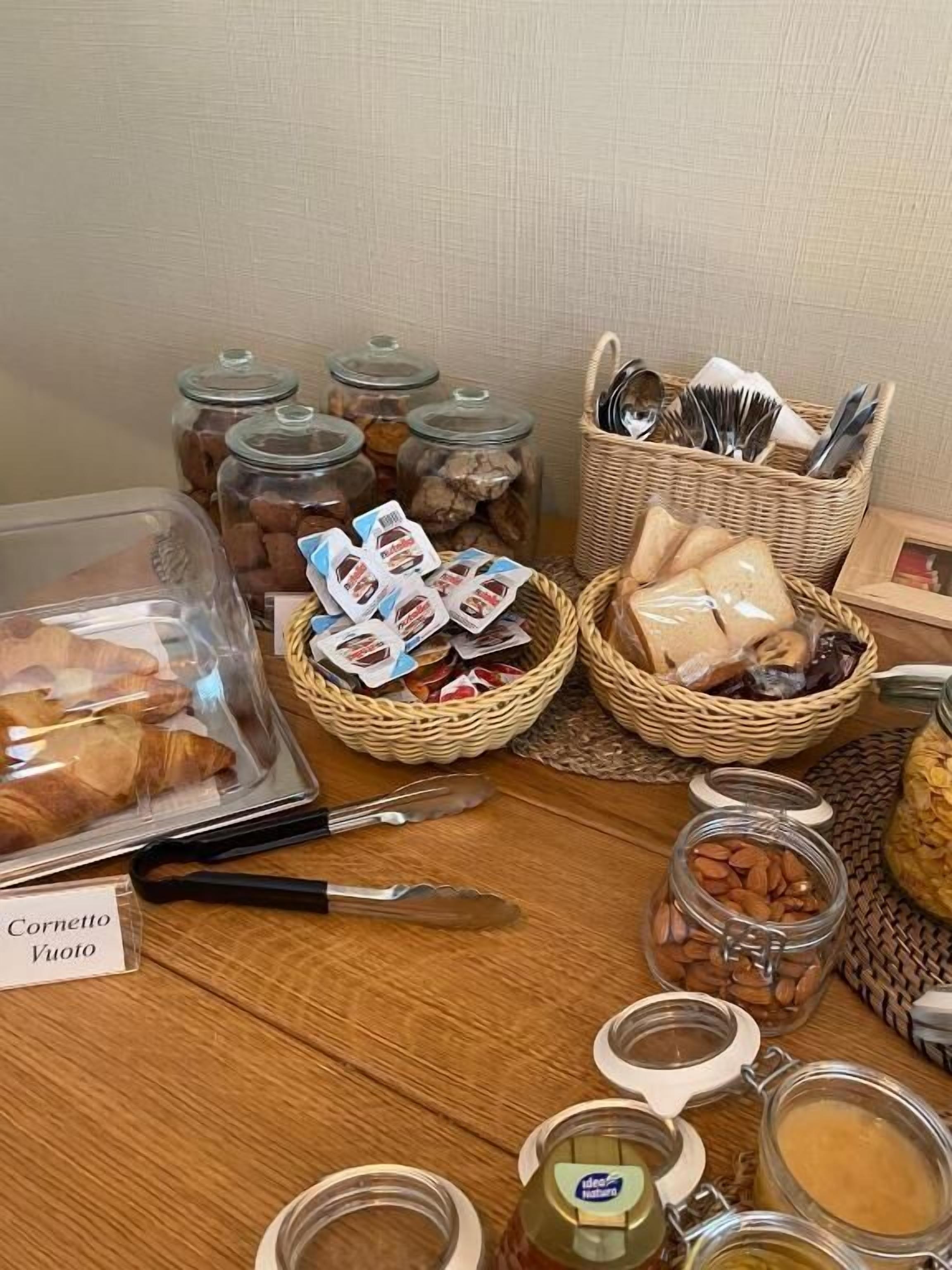 Een ontbijtbuffet met croissants, gebakjes en verschillende soorten beleg in glazen potten.