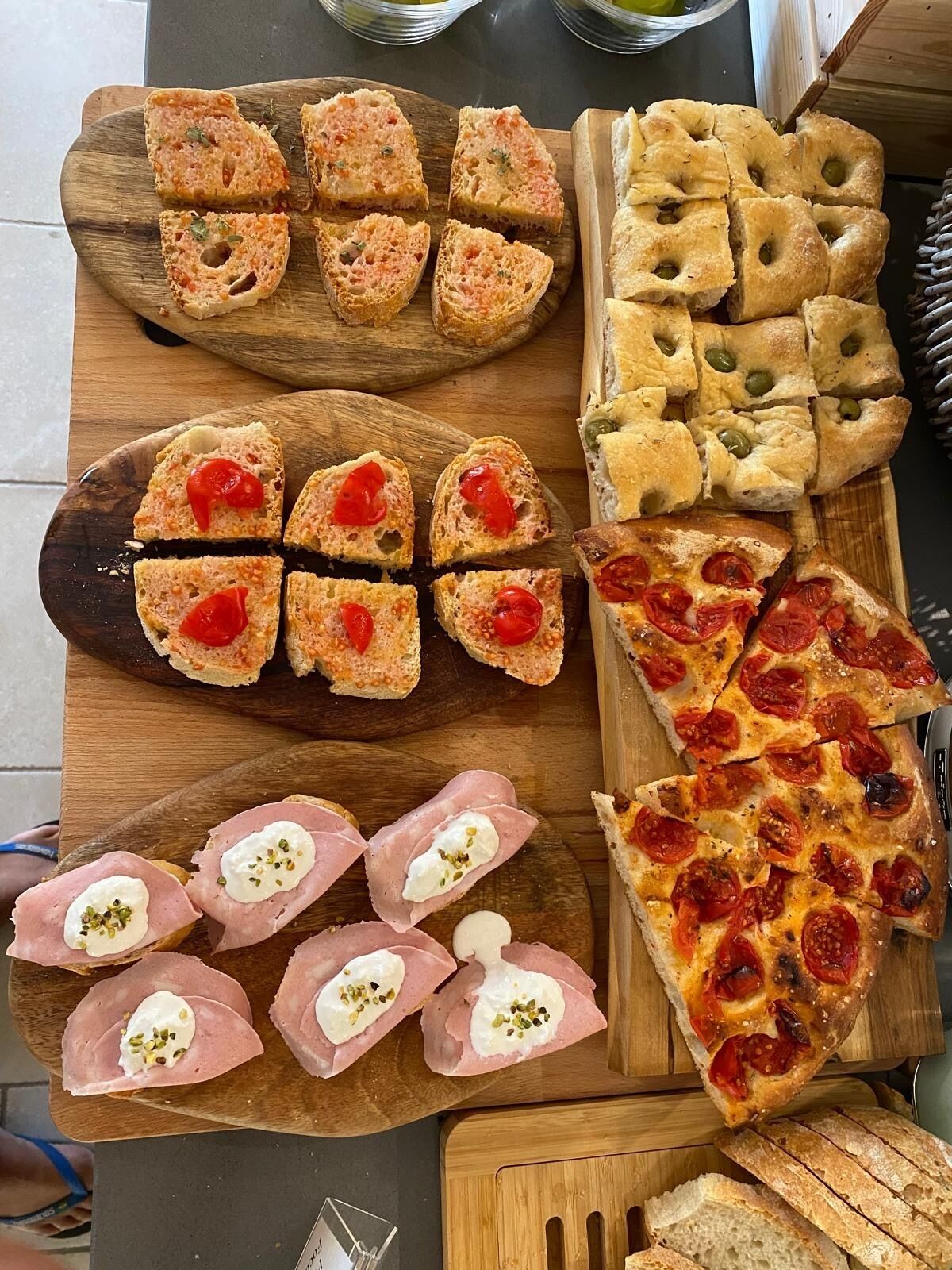 A variety of food items including bread, pizza, and sandwiches on wooden boards.