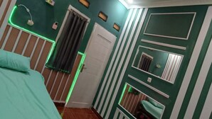 A bedroom with a bed, a chair, a small table, a door, and a mirror. - OYO Life 93158 Kost Asaka (Tangerang)