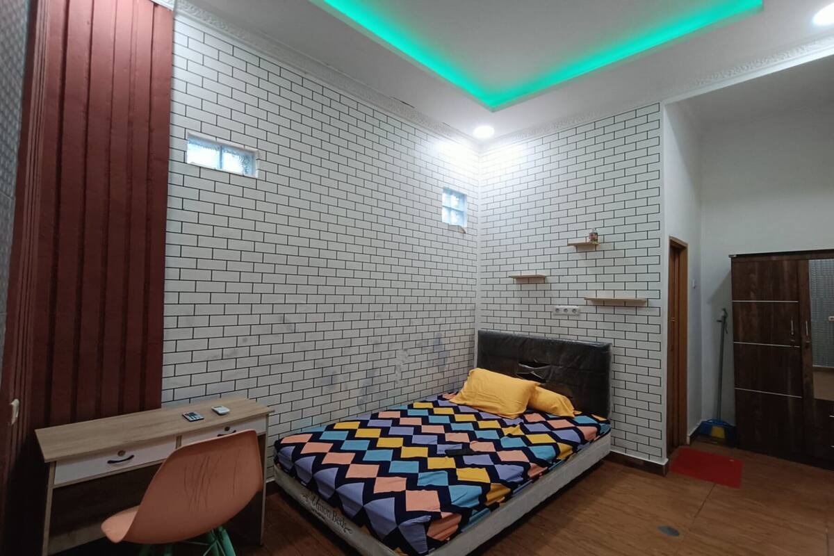 A bedroom with a bed, a desk, and a chair.
