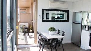 A modern kitchen with a built-in refrigerator, a dining area with a table and chairs, and a large window providing a view of the city. - Luxurious Flemington with Stunning Racecourse View (Kensington)