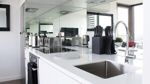 A modern kitchen with a large island, stainless steel appliances, and a large mirror. - Luxurious Flemington with Stunning Racecourse View (Kensington)