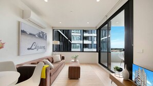 Una sala de estar moderna con un sofá, una mesa de centro y un televisor sobre un mueble de madera.