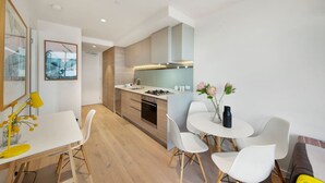 Una cocina moderna con armarios blancos, una isla central y un comedor con sillas blancas y una mesa pequeña.