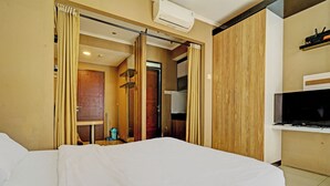 Une chambre d’hôtel équipée d’un lit, d’une télévision et d’une porte coulissante donnant accès à la salle de bain.