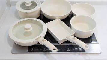 A kitchen with a stove, pots, pans, and a rice cooker.