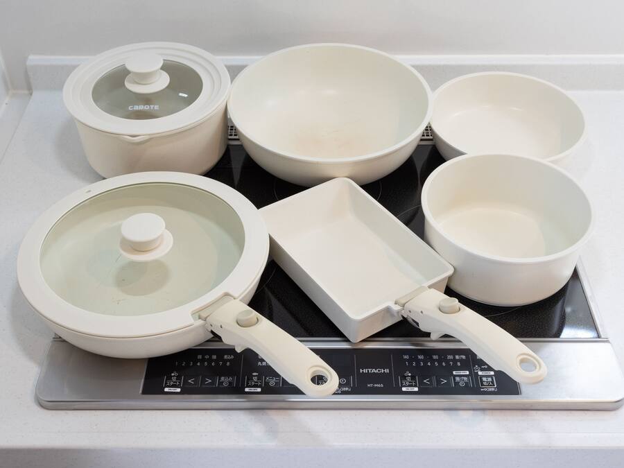 A kitchen with a stove, pots, pans, and a rice cooker.