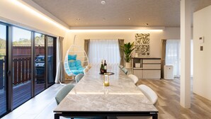 A spacious dining area with a marble table, comfortable seating, and a view of the outdoors. - SMART VILLA Hakone Sukumogawa Riverside (Hakone)