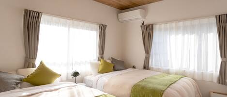 A hotel room with two beds, a wooden ceiling, an air conditioning unit, and large windows with curtains.