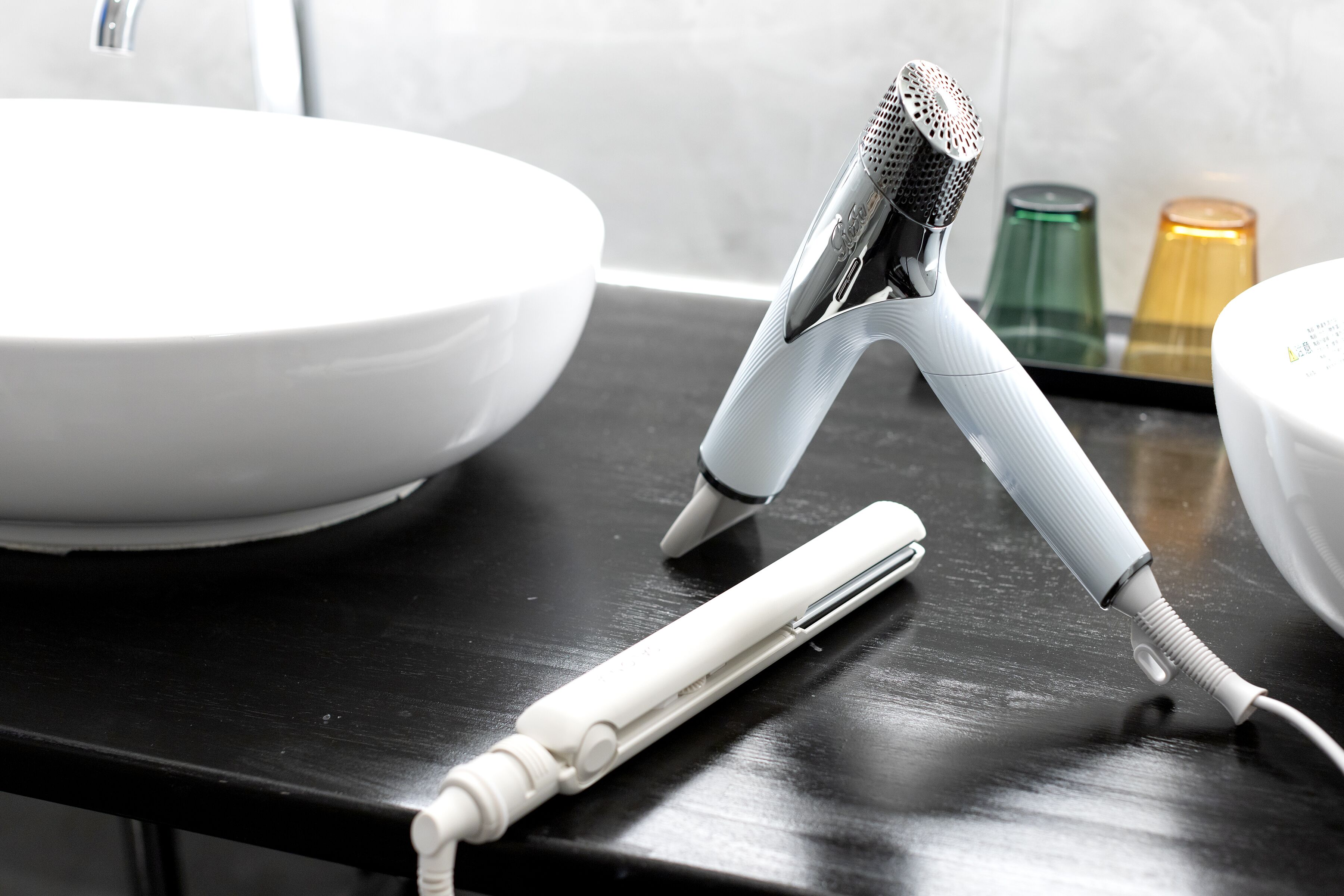 A bathroom with a white sink, a hairdryer, and a mirror.