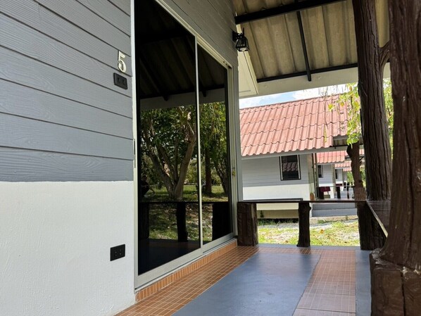 Un espace extérieur abrité, doté d’une porte-fenêtre coulissante donnant sur un jardin.