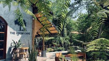 An outdoor seating area with tables and chairs, surrounded by lush greenery and ferns.