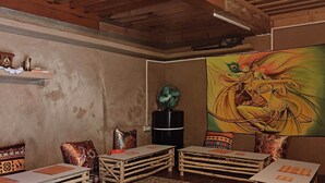 Une pièce chaleureuse, meublée de meubles en bois, avec un grand tableau au mur et une bouilloire posée sur la table.