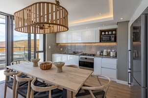 Una cocina moderna con armarios blancos, electrodomésticos de acero inoxidable y una mesa de comedor de madera con sillas.