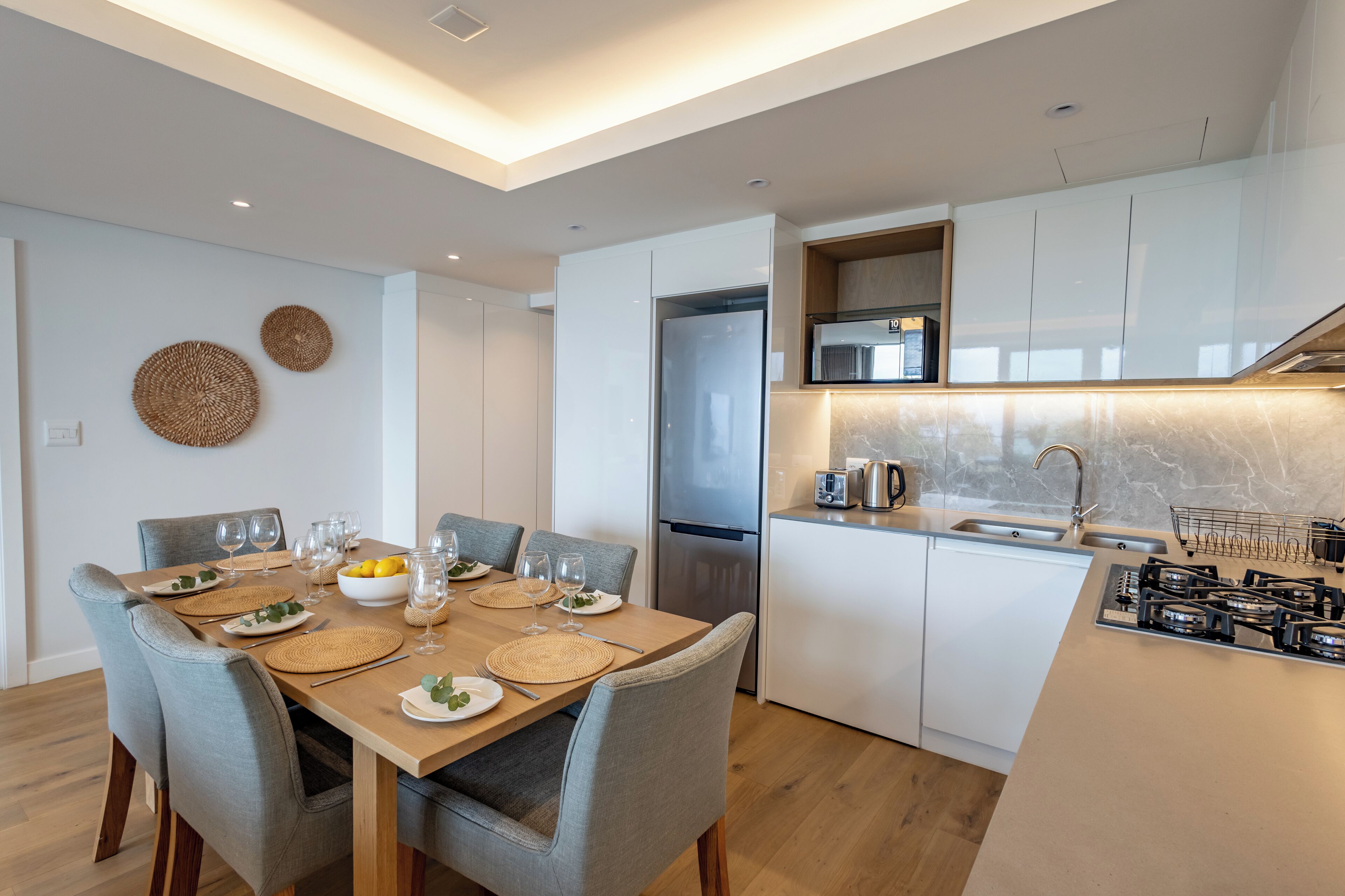 A modern kitchen with white cabinets, a stainless steel refrigerator, and a built-in microwave.