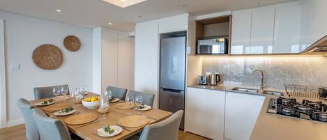 A modern kitchen with white cabinets, a stainless steel refrigerator, and a built-in microwave.