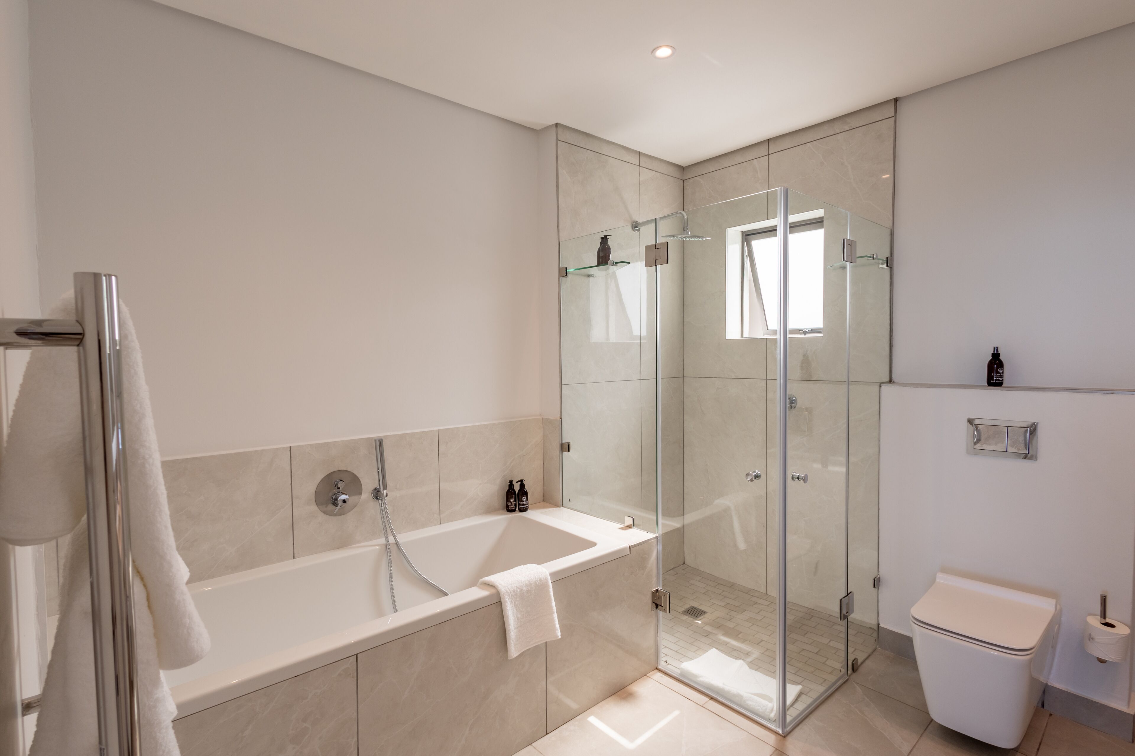 A modern bathroom with a glass-enclosed shower, a freestanding bathtub, and a toilet.