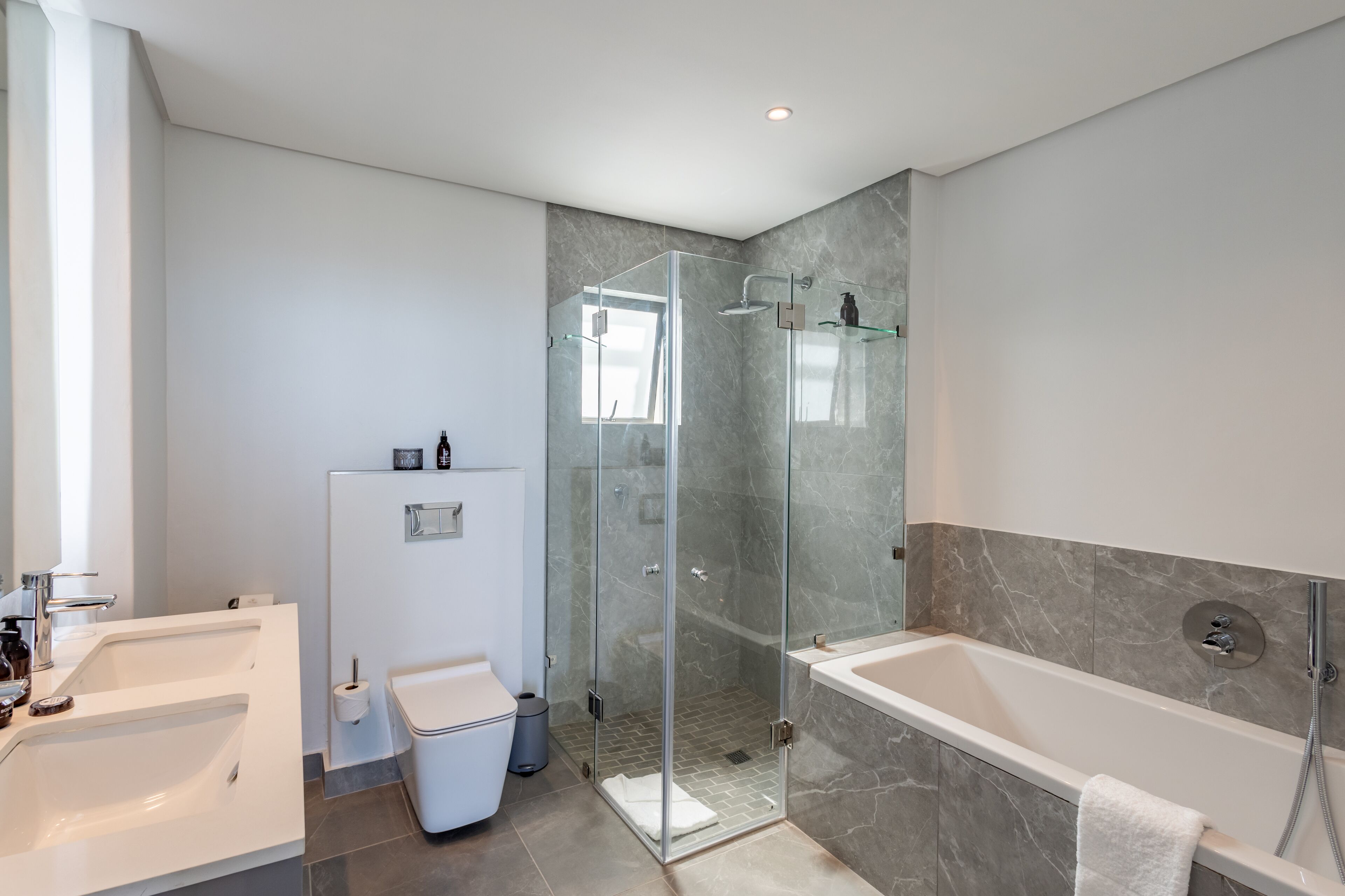 A modern bathroom with a glass-enclosed shower, a bathtub, and a separate sink.