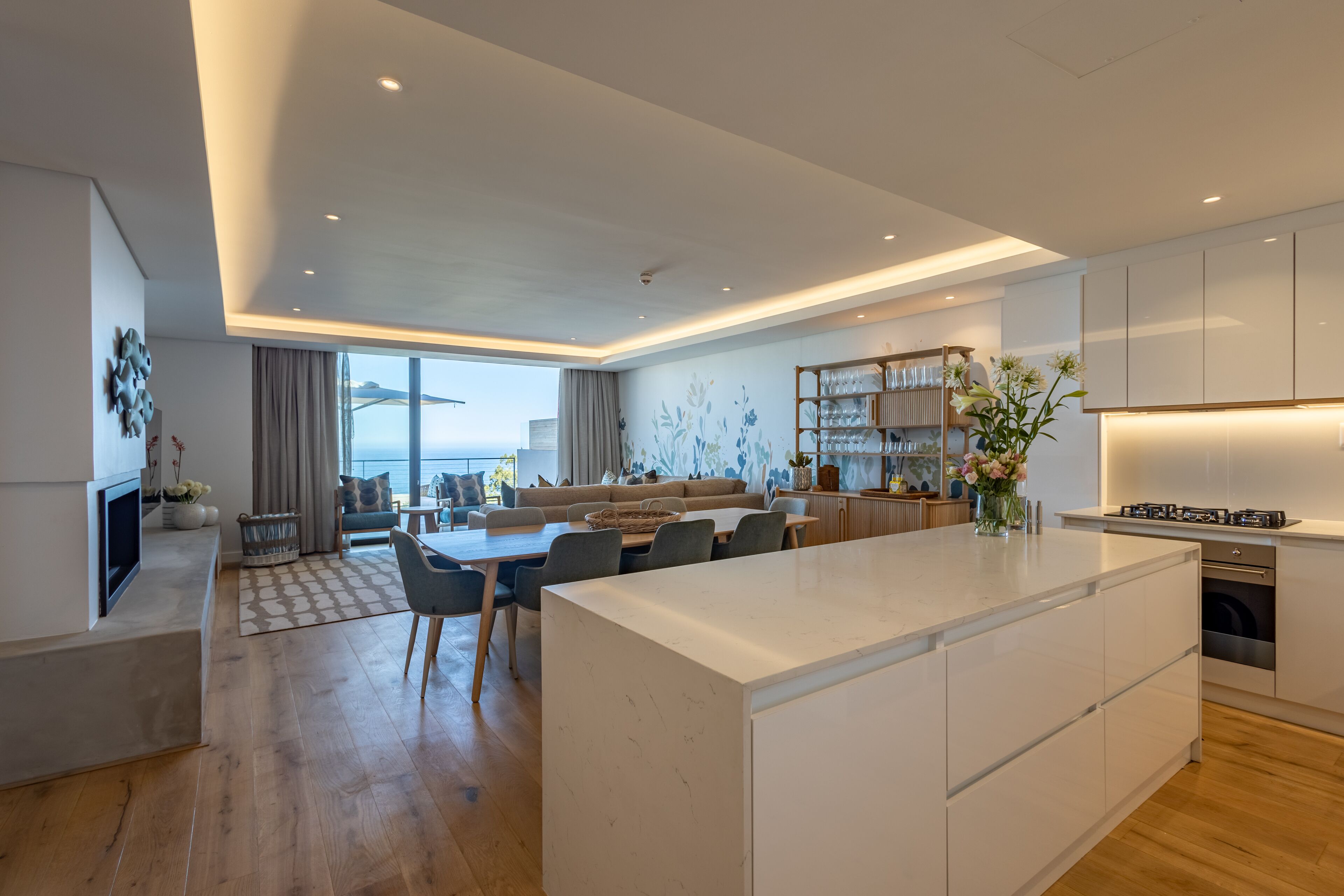A modern kitchen with a central island, built-in appliances, and a dining area with a sofa and chairs.