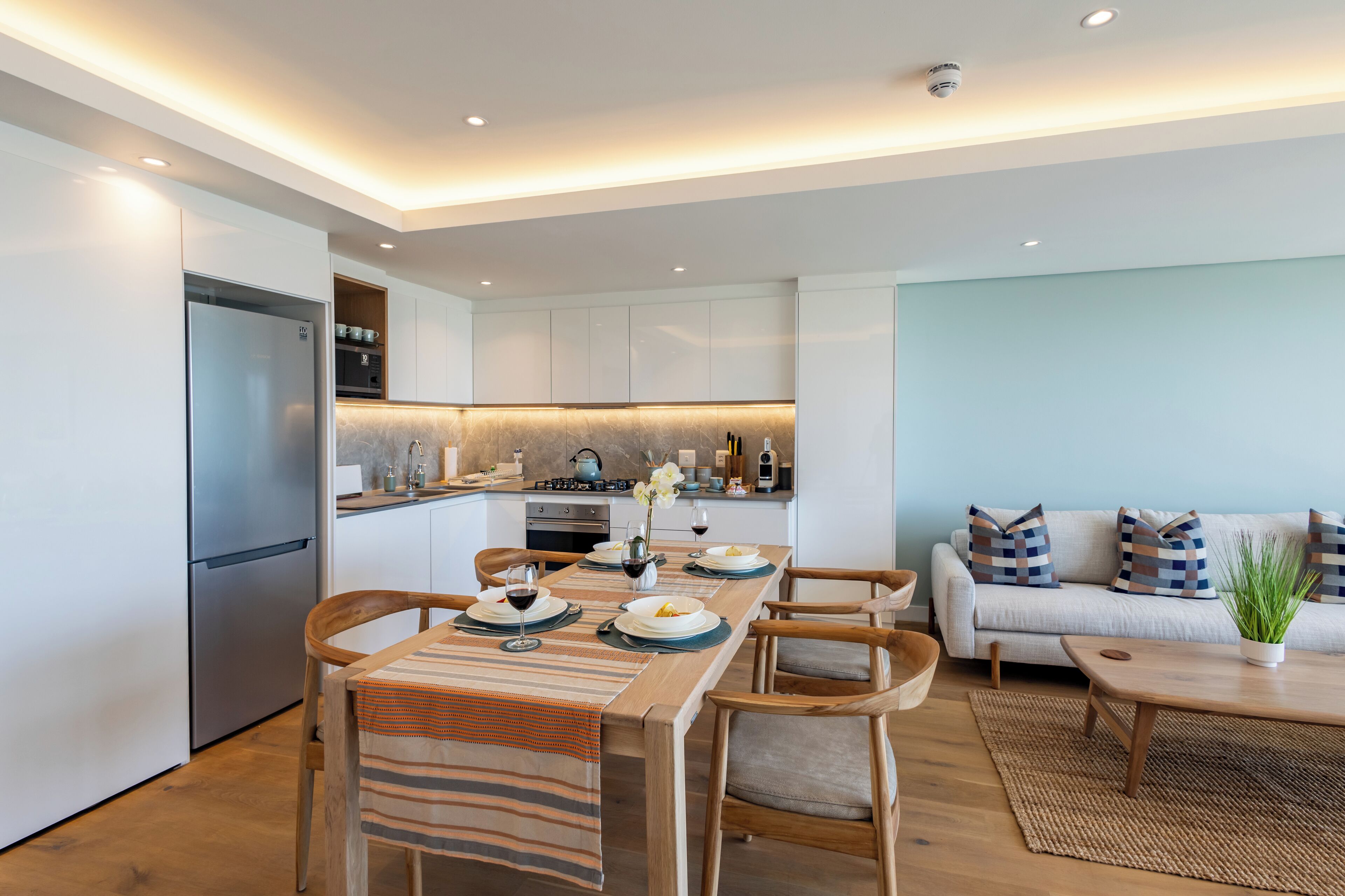 A modern kitchen with a dining area, a sofa, and a coffee table.