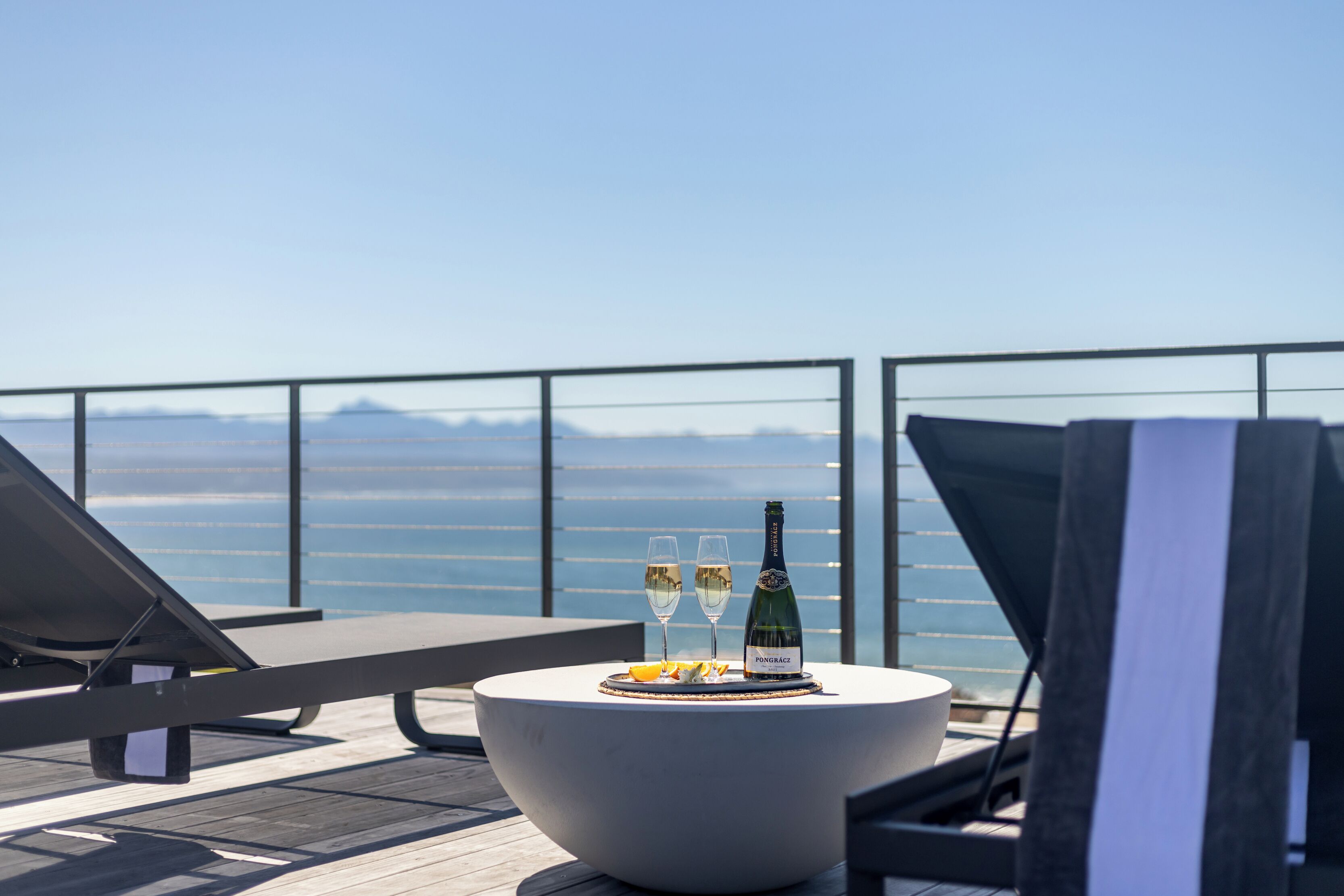 A balcony with a table set for two, featuring a bottle of champagne and glasses.