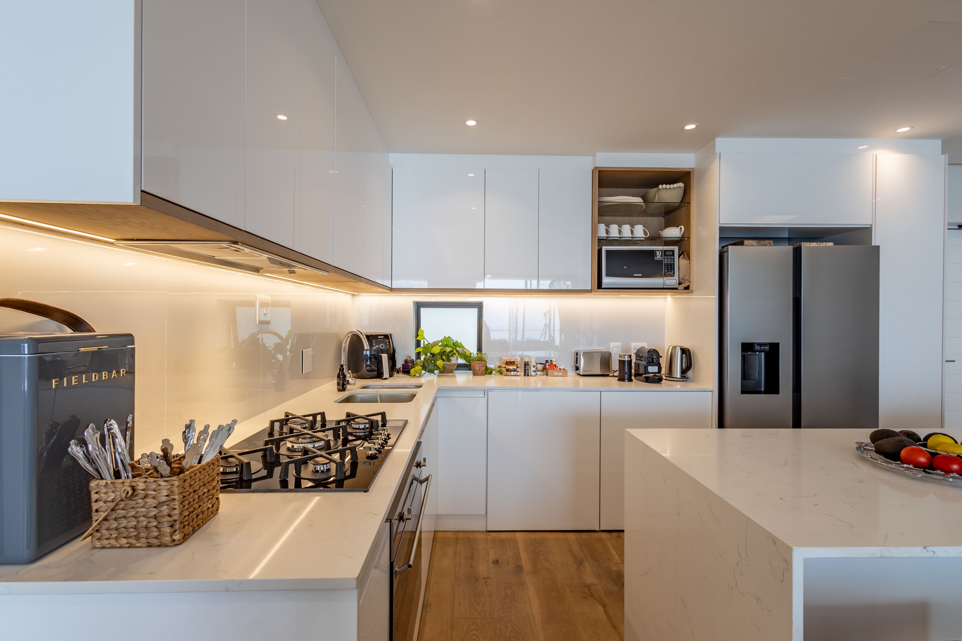 A modern kitchen with white cabinets, a gas stove, a microwave, and a refrigerator.