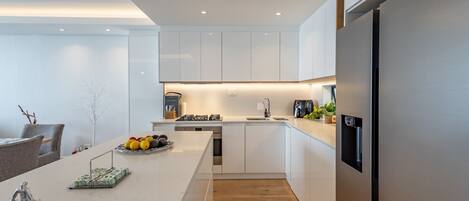 A modern kitchen with white cabinetry, a central island, and a built-in refrigerator.