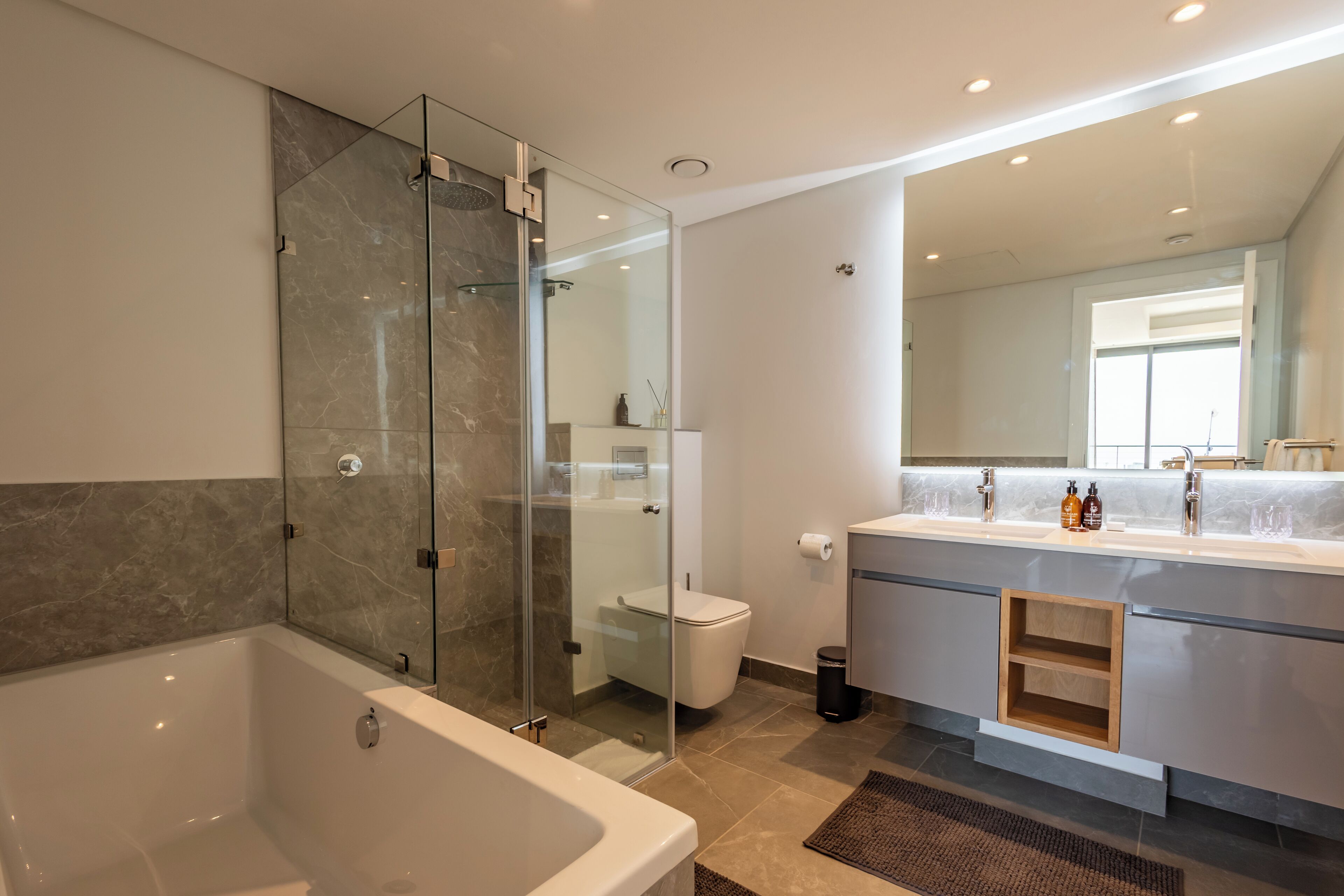 Une salle de bain moderne dotée d’une douche à parois de verre, d’une grande baignoire et d’un meuble-lavabo avec un miroir.